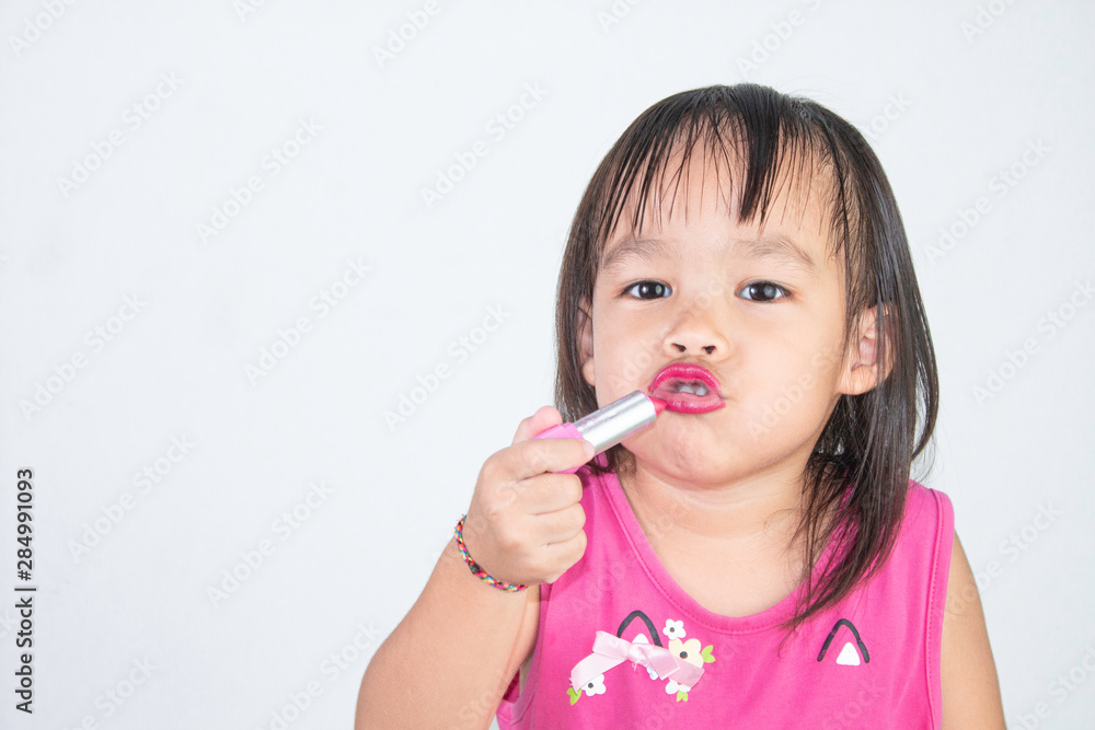 Happy Asian child girl with apply red lipstick wearing pink dress isolated on white background. Happy Asian child girl with apply red lipstick wearing pink dress isolated on white background.