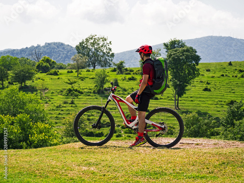 Side view of sports man on mountain bike at rural alpine fields background