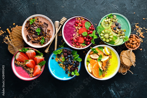 A great set of colored fruit smoothies with yogurt, fresh fruit and berries. A healthy breakfast. Top view. Free space for your text. On a black background.