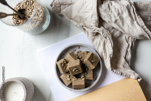 Portion of halva with vanilla and sunflower seeds on marble background with copy space
