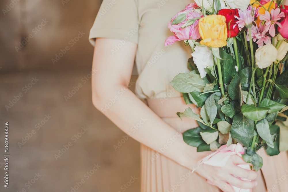 Beautiful middle-eastern girl with a bouquet of flowers in hands. Young attractive female with flowers. Portrait of charming, pretty girl holding flowers bouquet