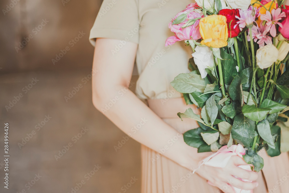 Beautiful middle-eastern girl with a bouquet of flowers in hands. Young attractive female with flowers. Portrait of charming, pretty girl holding flowers bouquet Beautiful middle-eastern girl with a bouquet of flowers in hands. Young attractive female with flowers. Portrait of charming, pretty girl holding flowers bouquet