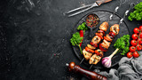 Chicken shish kebab with onions and tomatoes. Barbecue. On a black background. Top view. Free space for your text. Rustic style.