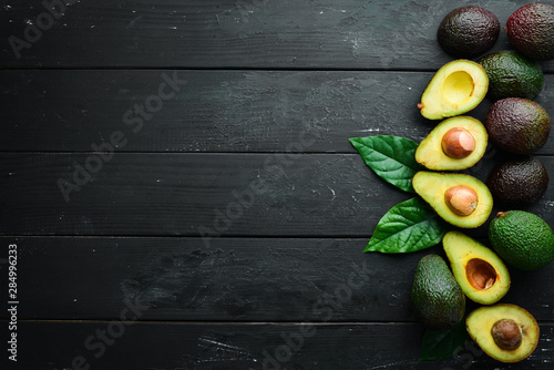 Fresh avocado with leaves on a black background. Top view. Free space for your text. photo
