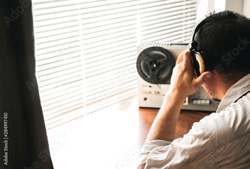 Special agent listens on the reel tape recorder. Officer wiretapping in headphones. KGB spying of conversations.  Cold war period. photo