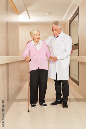 Arzt und gebrechliche alte Frau mit Krückstock