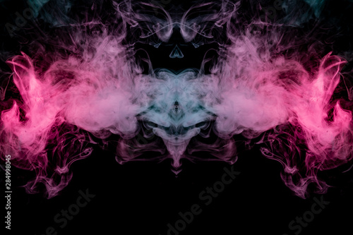 Smoke of different blue, red and pink colors in form of horror in the shape of the head, face and eye with wings on a black isolated background. Soul and ghost in mystical symbol. Print for clothes.