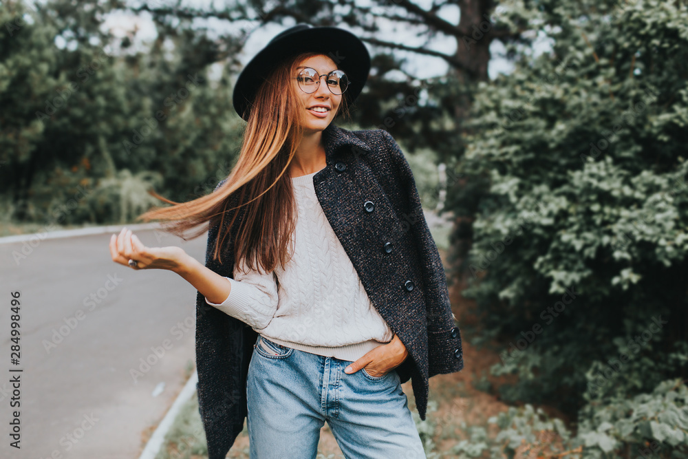 Naklejka premium Beautiful Autumn Woman with Autumn Leaves on Fall Nature Background. season and people concept - beautiful happy young woman walking in autumn park. girl in good mood posing in autumn day, enjoying