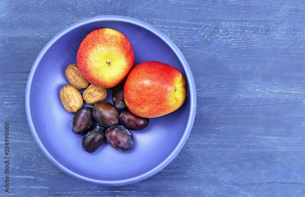 blue fruit bowl with apples, walnuts and plums blue fruit bowl with apples, walnuts and plums