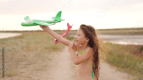 Two sisters running on coast and playing with toy planes.
