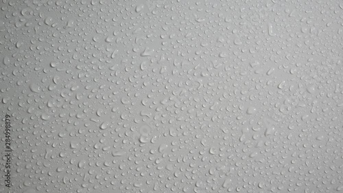Rain water drops flow down a smooth white wall. Close up. Slow motion