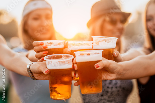 Female friends cheering with beer at music festival photo