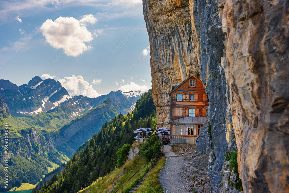 Swiss Alps and a restaurant under a cliff on mountain Ebenalp in Switzerland - obrazy, fototapety, plakaty 