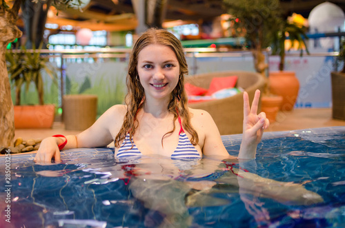 Young Caucasian girl relaxing in the pool in a closed winter water Park. Having a good time. He smiles and looks at the camera. Holiday  Spa  weekend concept 