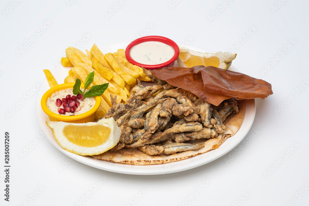 Grilled Sardines plate served with sauce, hummus dip and fries isolated on white background