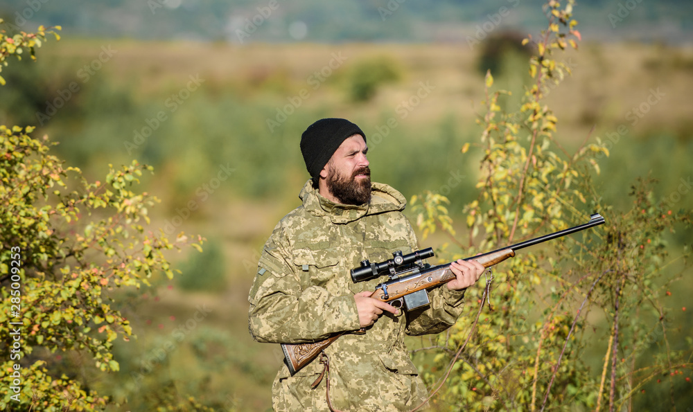Fototapeta premium Hunting masculine hobby. Man brutal gamekeeper nature background. Hunter hold rifle. Bearded hunter spend leisure hunting. Focus and concentration of experienced hunter. Hunting and trapping seasons