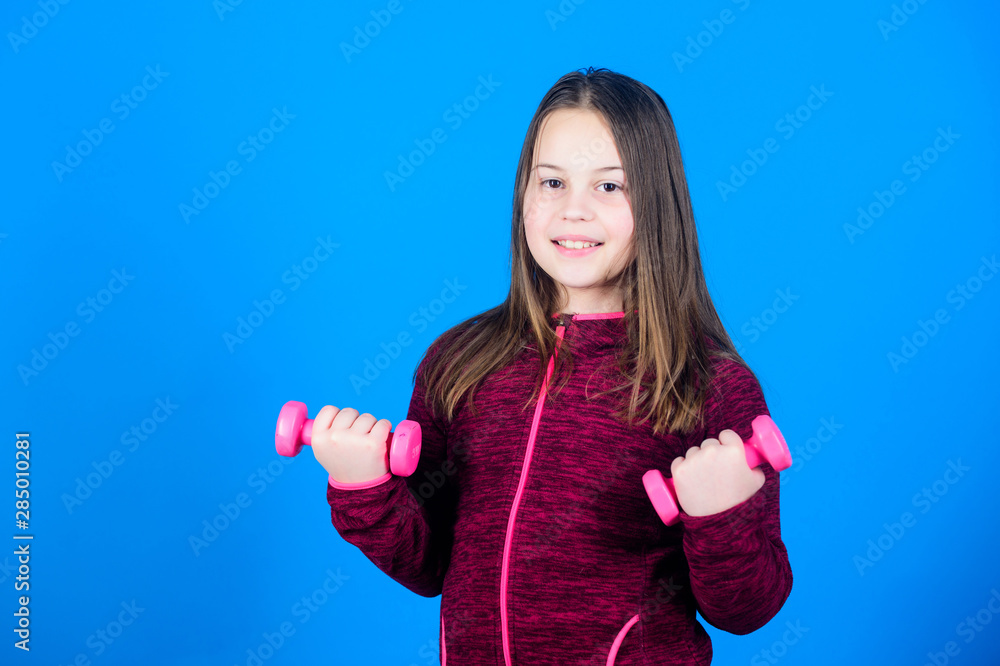 Child hold little dumbbell blue background. Sport for teens. Easy exercises with dumbbell. Toward stronger body. Rehabilitation concept. Girl exercising with dumbbell. Beginner dumbbell exercises Child hold little dumbbell blue background. Sport for teens. Easy exercises with dumbbell. Toward stronger body. Rehabilitation concept. Girl exercising with dumbbell. Beginner dumbbell exercises
