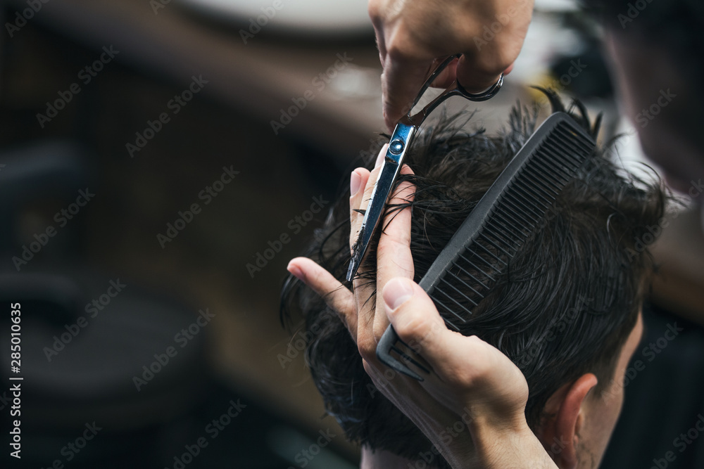 Barbershop. Close-up of man haircut, master does the hair styling in barber shop. Close-up, master Barber does the hairstyle and styling with scissors. Concept Barbershop. - obrazy, fototapety, plakaty 