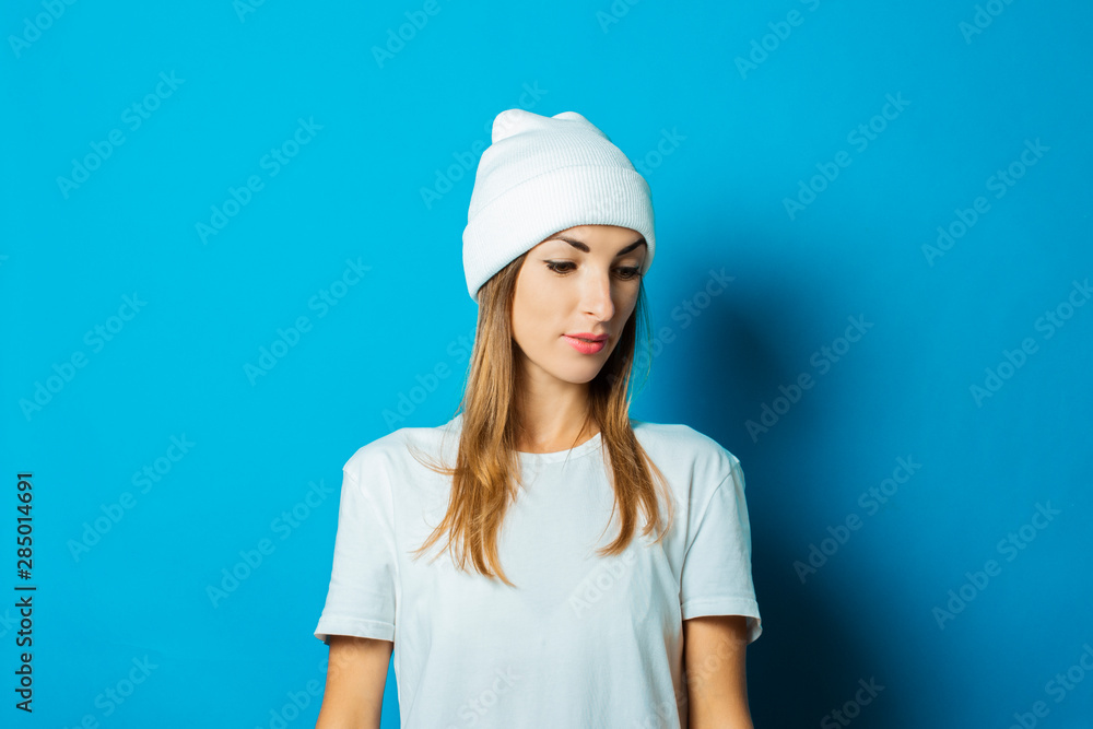 Young woman in white hat and t-shirt on a blue background Young woman in white hat and t-shirt on a blue background