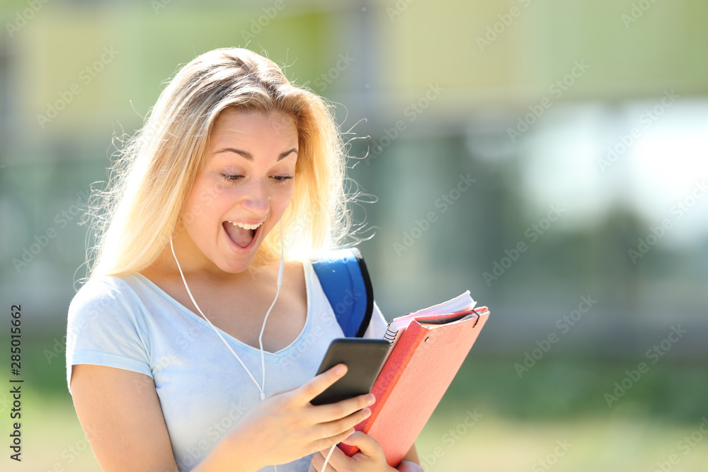 Obraz premium Surprised student checking phone messages in a campus