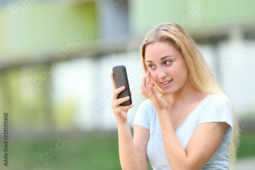 Teen using smart phone as a mirror outdoors