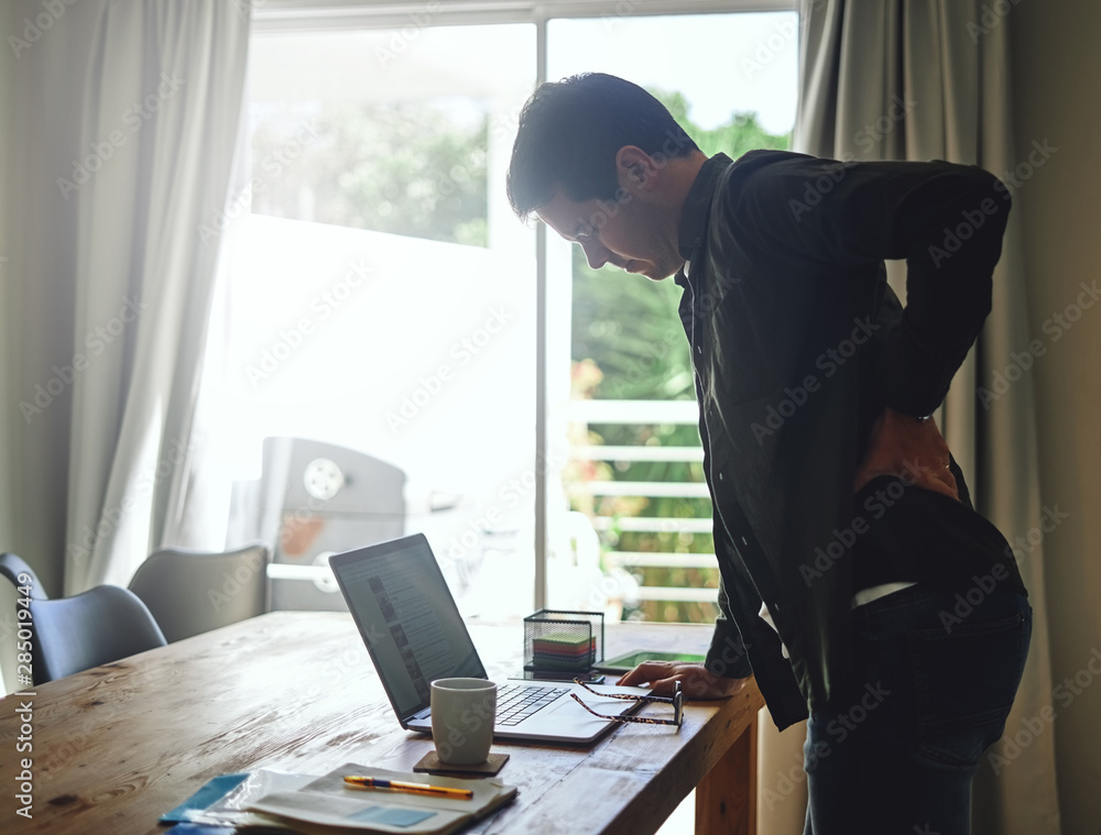 Man suffering from backache while working at laptop Man suffering from backache while working at laptop