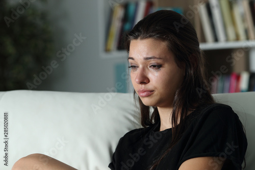 Sad girl crying looking away alone at home