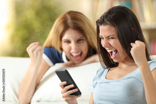 Excited friends checking phone news at home