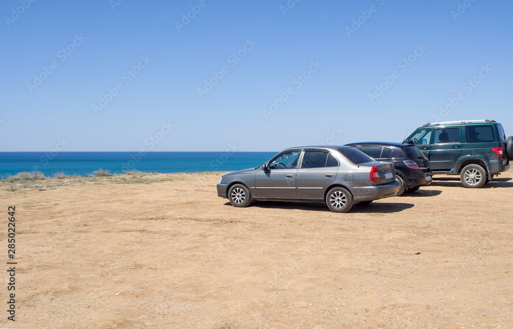 Cars stand on the beach in a clear summer afternoon, an impromptu Parking lot came to rest the owners of cars , copy space.