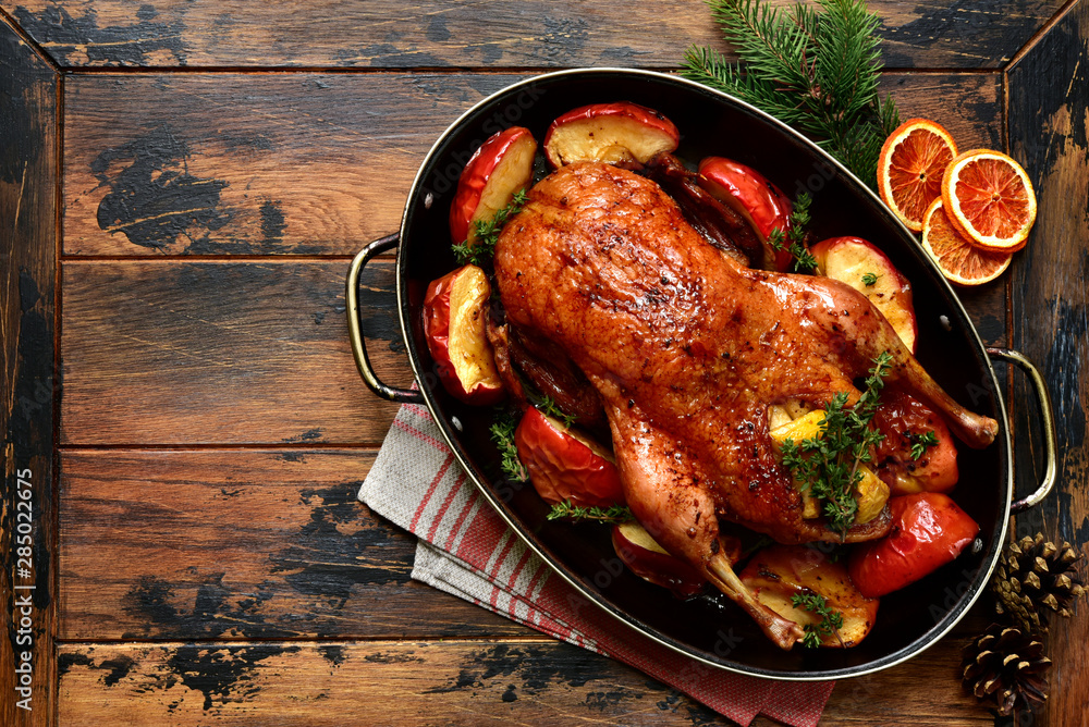 Roast goose stuffed with baked apples in a skillet, festive christmas recipe. Top view with copy space. - obrazy, fototapety, plakaty 
