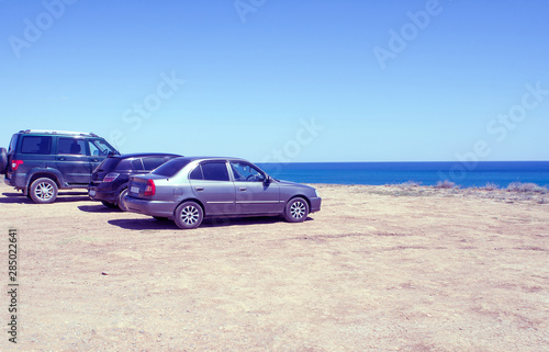 Cars stand on the beach in a clear summer afternoon, an impromptu Parking lot came to rest the owners of cars , copy space, instagram. © OlegSinar