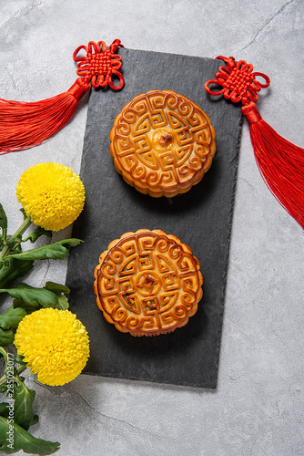 Chinese Mid-Autumn Festival cuisine, mooncakes and chrysanthemums on a cement textured background