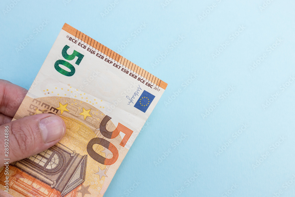 Hand holding Euro currency cash bank notes money blue background