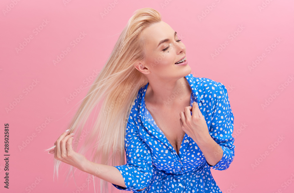 Beauty Portrait of a beautiful young blond woman with amazing flowing hair. loose hair fluttering in the wind. Isolated on pink studio background. fresh air concept. Climate control Beauty Portrait of a beautiful young blond woman with amazing flowing hair. loose hair fluttering in the wind. Isolated on pink studio background. fresh air concept. Climate control
