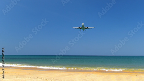 Commercial plane landing at Phuket International Airport on tropical beach and blue sky background, travel concept and business transportation idea