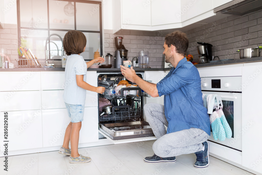 Foto Father and son loading dishwasher together