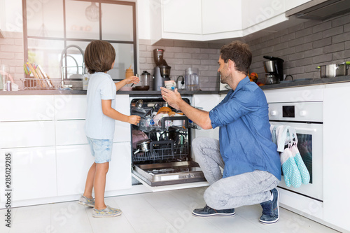 Father and son loading dishwasher together photo