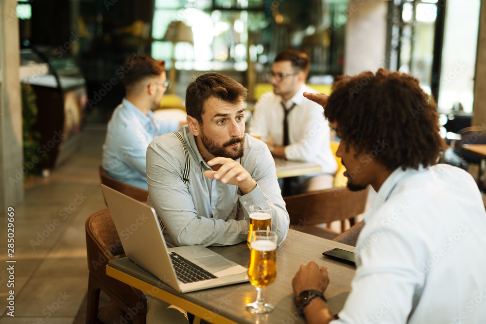Men are sitting at table in modern cafe. Talk about work Men are sitting at table in modern cafe. Talk about work
