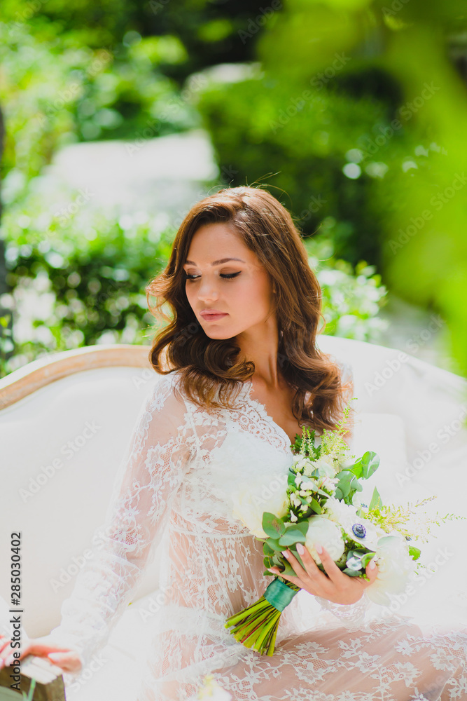 Close-up portrait of young beautiful bride in white negligee with bridal bouquet Close-up portrait of young beautiful bride in white negligee with bridal bouquet
