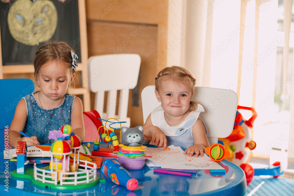 Fototapeta premium Little cute girls play in the room. Development and social learning