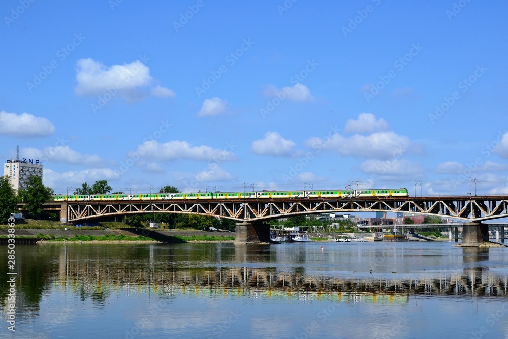 Warsaw, Poland. The geen and yellow train crossing the Srednicowy Bridge in Warsaw, Poland. It is a railway bridge over the Vistula River in Warsaw, north of the Poniatowski Warsaw, Poland. The geen and yellow train crossing the Srednicowy Bridge in Warsaw, Poland. It is a railway bridge over the Vistula River in Warsaw, north of the Poniatowski