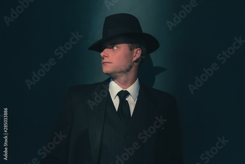 Retro man in hat wears suit and tie.