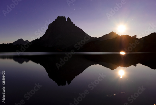 The full moon rises behind Mount Midi d'Ossau and is reflected in the gentau lake, Ayous Lakes, France