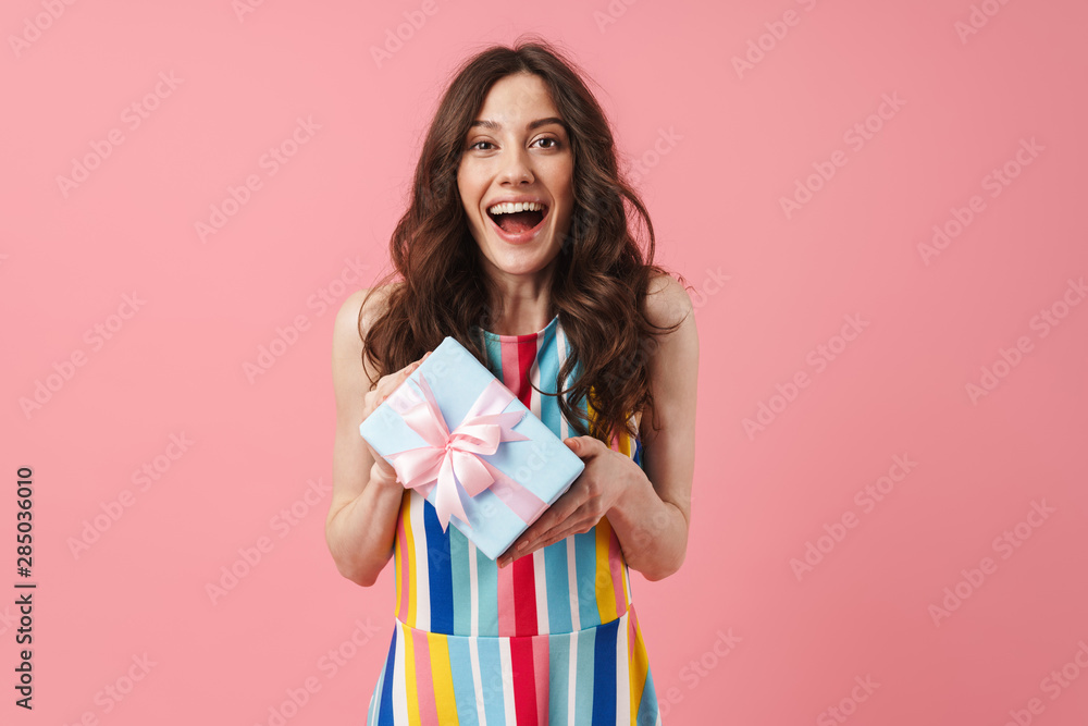Pretty cheerful smiling positive cute woman posing isolated over pink wall background holding present gift box. Pretty cheerful smiling positive cute woman posing isolated over pink wall background holding present gift box.
