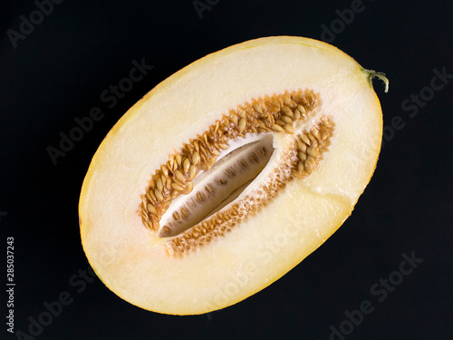 half of the ripe amal melon with seeds on a black background photo