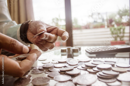 фотографія Cropped Image Of Businessman counting coins Using Calculator at Desk In Office