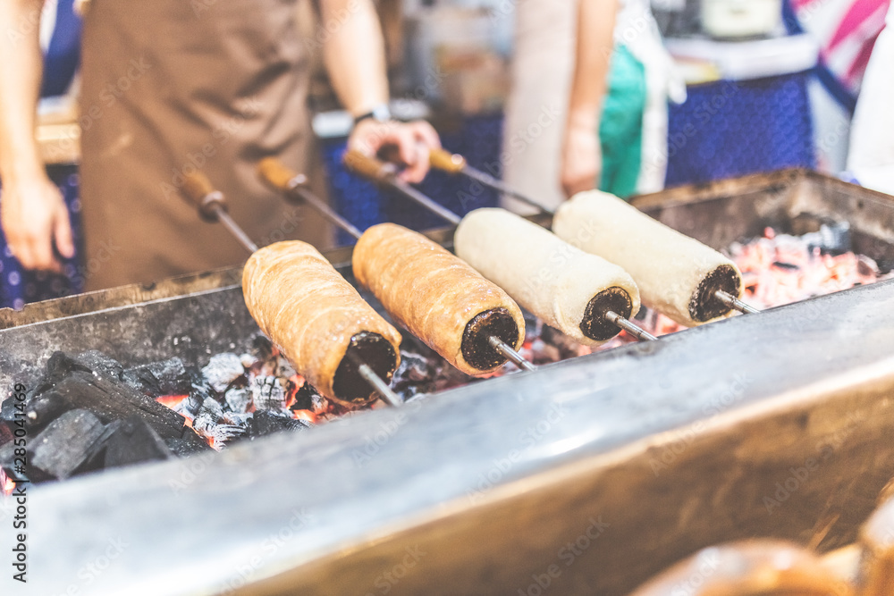 Kurtos kalacs or Chimney Cakes roll spinning over hot coals at a market stand,the typical sweet of Budapest,Hungary