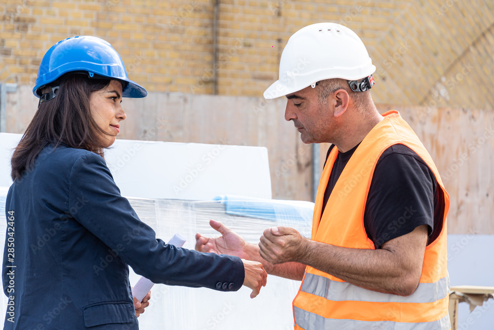 Female construction boss talking to a foreman. Profile. Outdoors Female construction boss talking to a foreman. Profile. Outdoors