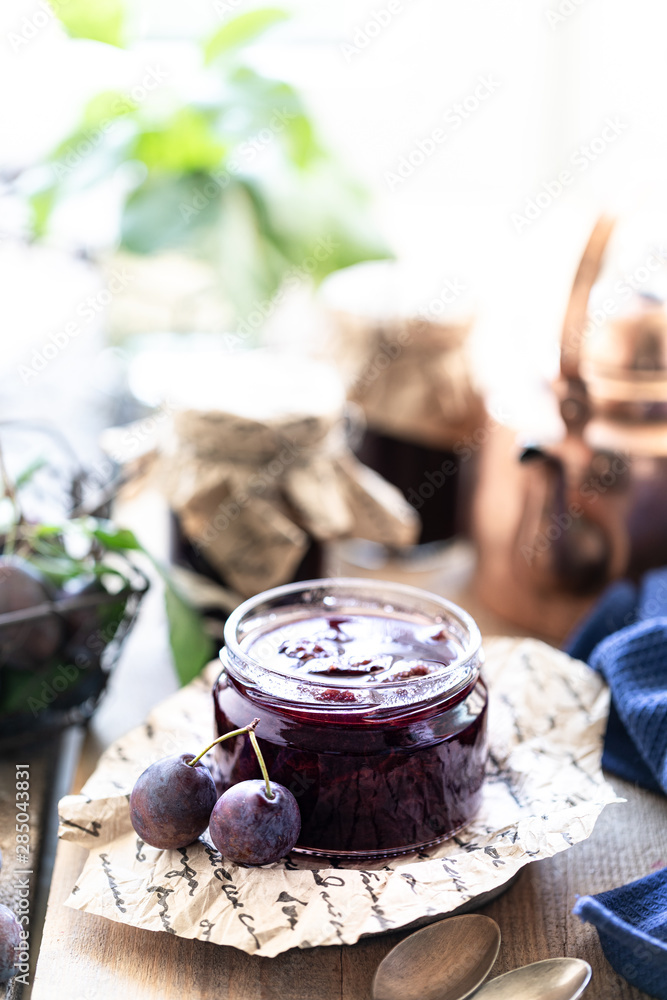 Sweet homemade plum jam and fruits on a wooden table