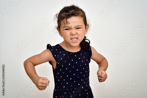 Angry and aggressive young girl with clenched teeth and fists looking at the camera